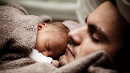 Baby ligger på pappas bryst, begge sover.